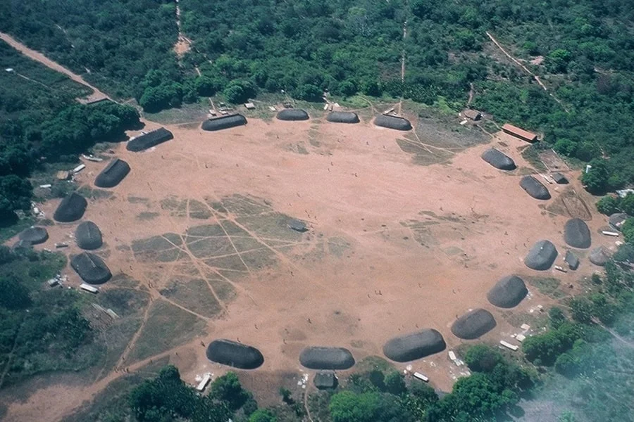 Foto aérea da aldeia Kuikuro II no Território Indígena do Xingu mostrando ocas indígenas formando o círculo da aldeia com a floresta em volta