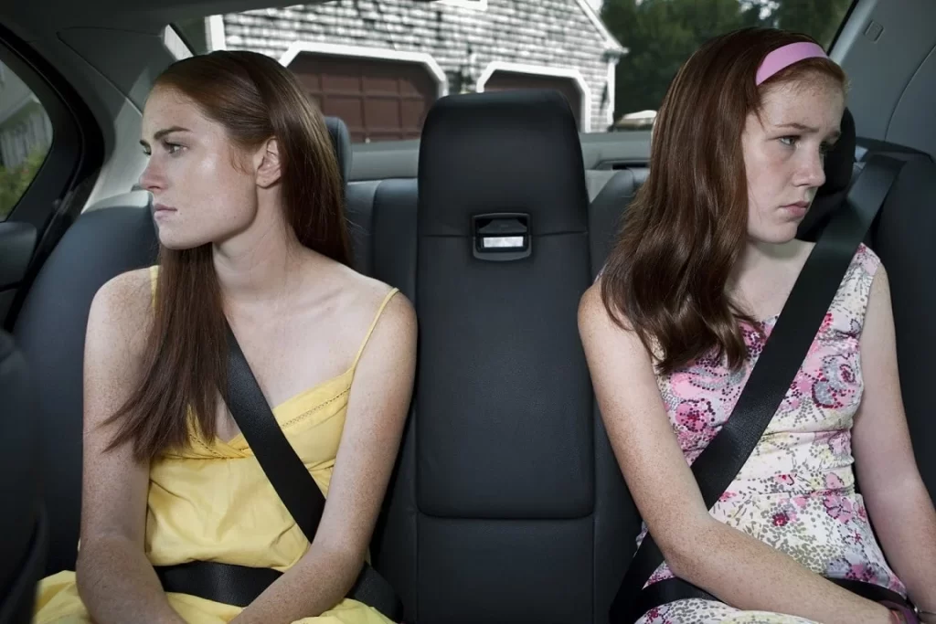 duas garotas sentadas em um carro olhando para lados opostos