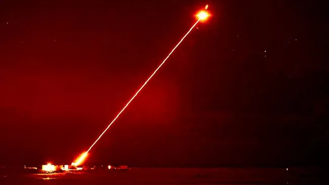 Um laser vermelho saindo do chão e atingindo um objeto no céu noturno