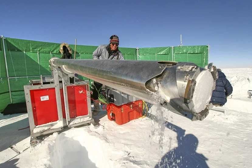 Pesquisador usando um perfurador de gelo metálico cilíndrico coletando um núcleo de neve