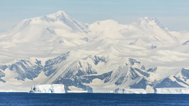 Montanhas cobertas de neve em frente ao oceano