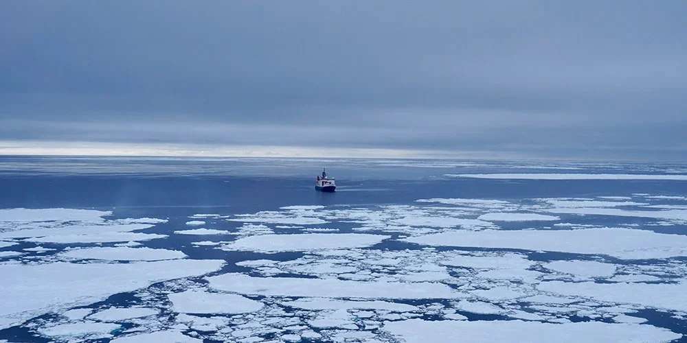 Barco navegando em mar com placas de gelo