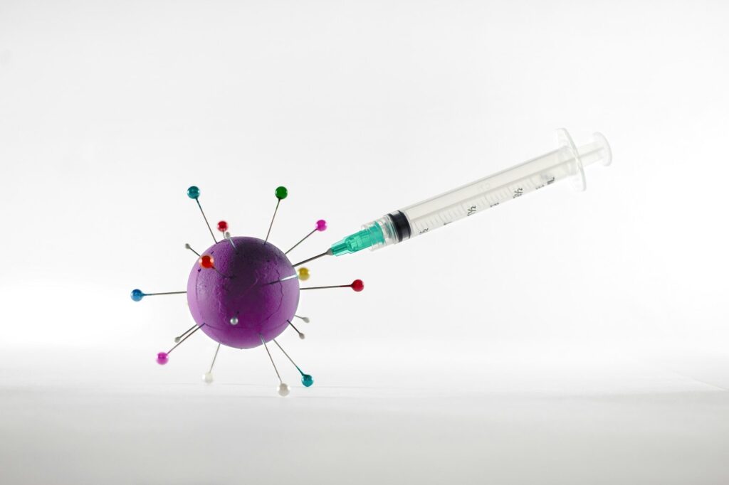 seringa sendo espetada em uma bola simulando um vírus