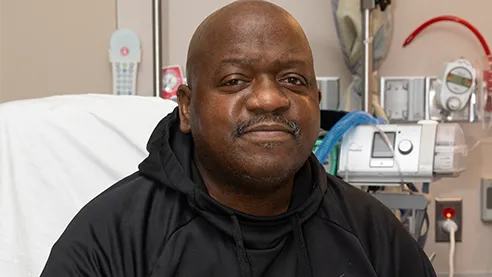 Slayman, homem negro de camisa preta, em cama de hospital, que morreu após transplante com rim de porco.