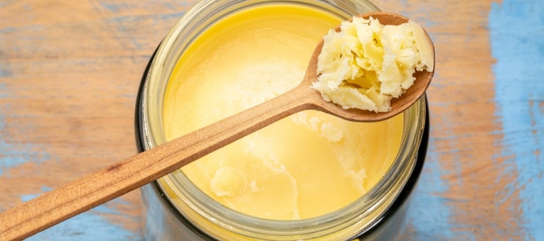 pote com manteiga vegana e uma colher de pau cheia dela