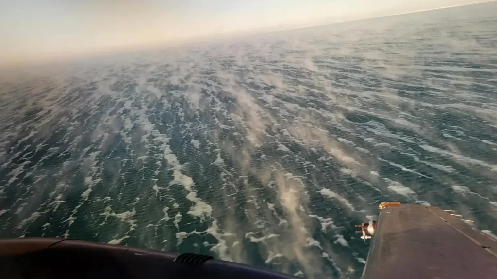 Esta imagem, tirada da aeronave King Air — a asa esquerda é visível no canto inferior direito —, mostra uma fenda aberta e as nuvens nascentes sobrejacentes, comumente chamadas de fumaça marítima.