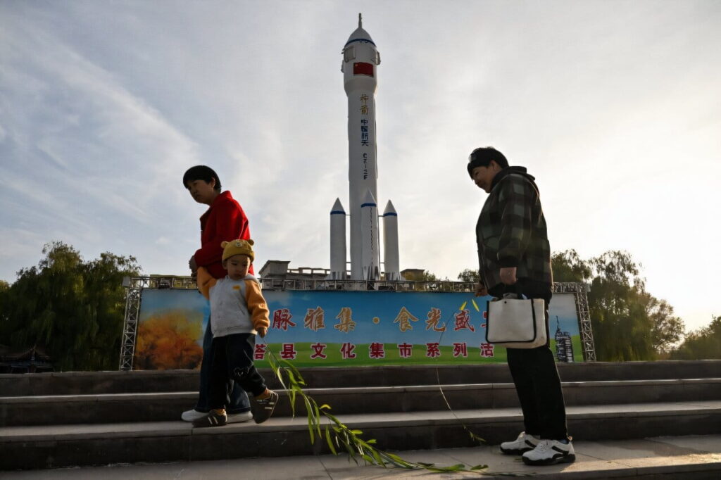 Chineses em frente a um foguete espacial
