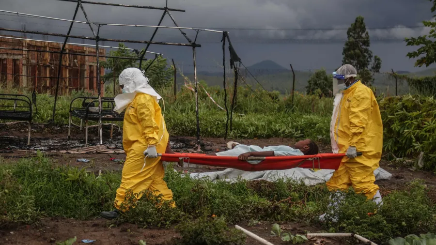 Médicos paramentads carregando um paciente de ebola em uma maca
