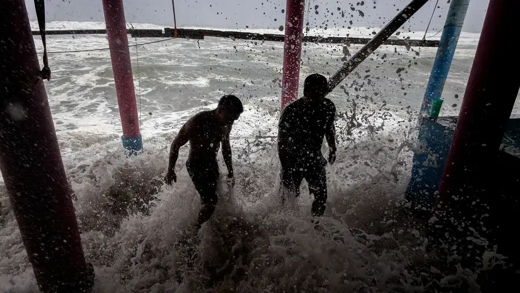 Moradores colocam sacos de areia como barreira protetora contra as fortes ondas geradas pelo furacão Polo na Praia Azul, no município de Lázaro Cárdenas, Michoacán, México, em 23 de setembro de 2026.
